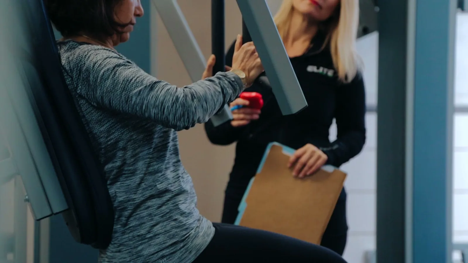 Elite Strength & Fitness trainer coaching a client through a machine exercise in the Winter Park studio